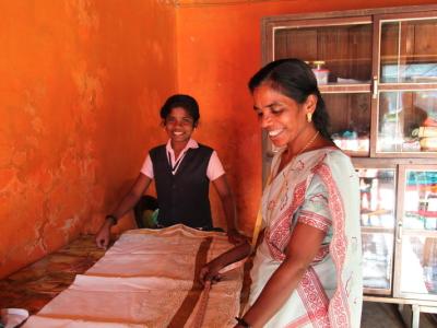 Woman tailor while daughter helps in India