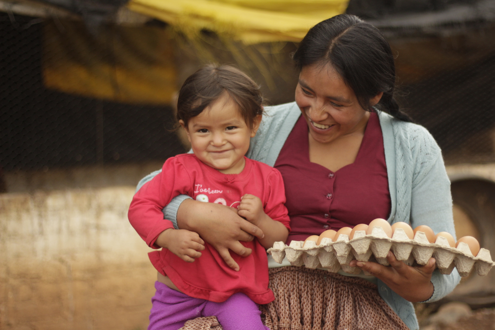 Nora with her youngest daughter shows the eggs she collects daily from her chicken pen in Bolivia. 