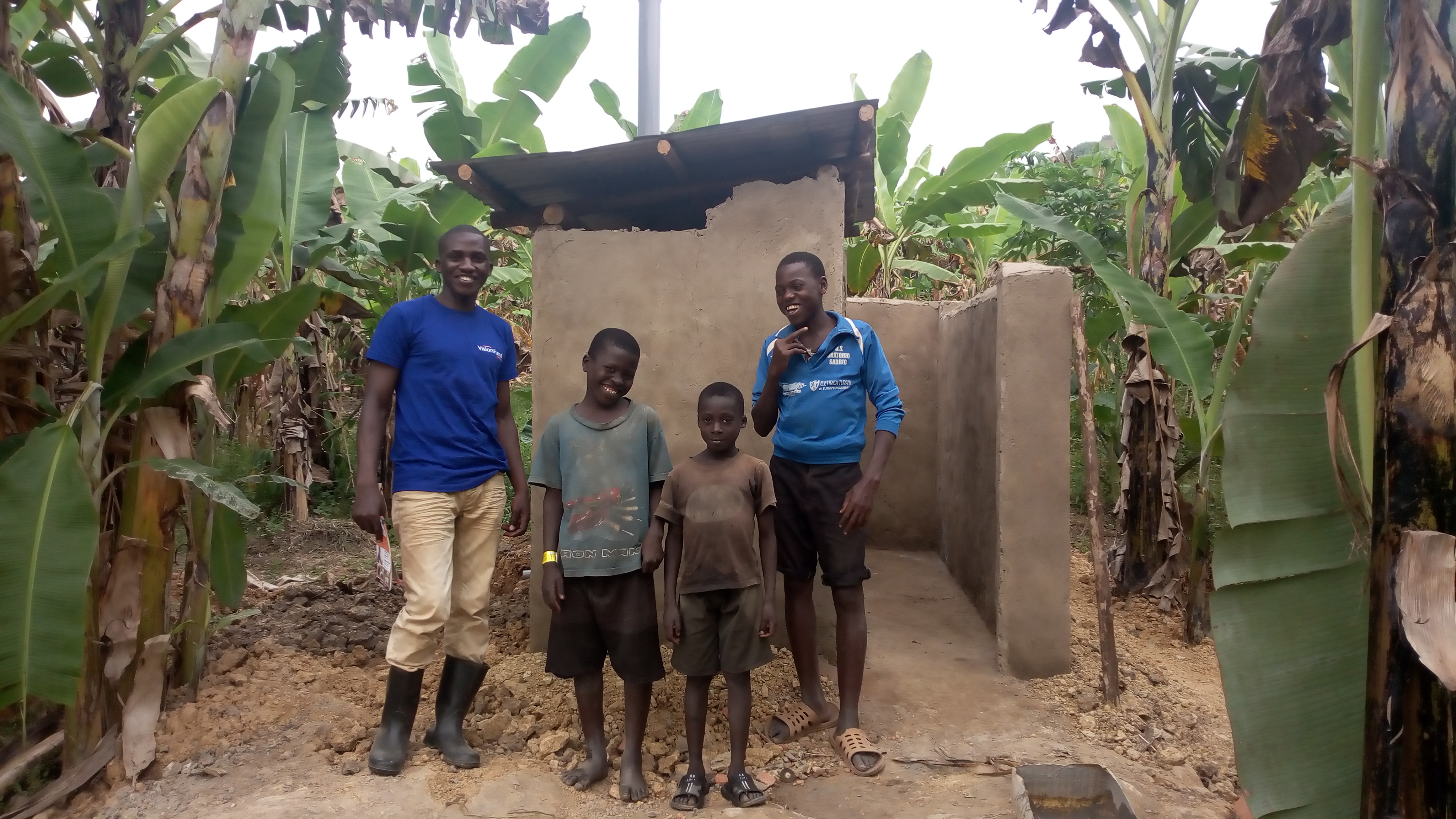 Children of Jane Natenza stand near their newly constructed toilet with a loan from VisionFund.