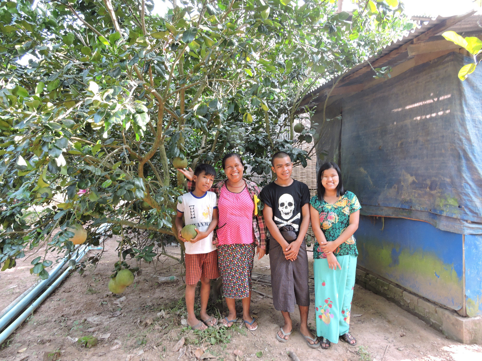 family in front of pomelo trees on their farm in Myanmar