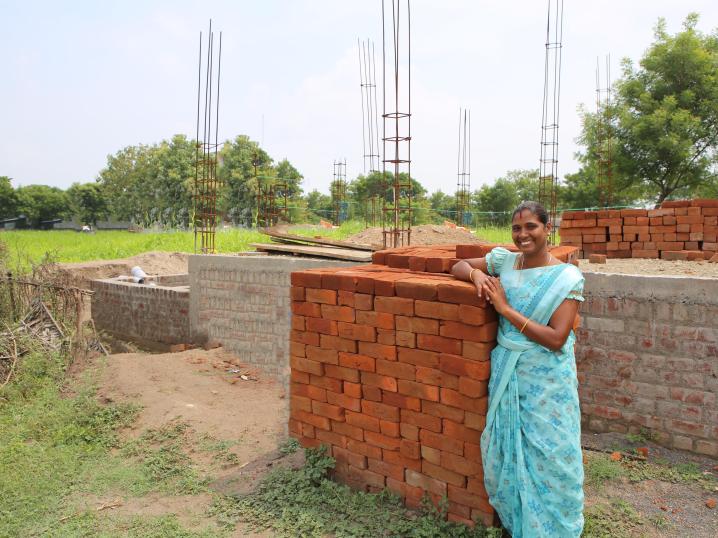 VisionFund India client Dhanalakshmi in front of her future building to employ women