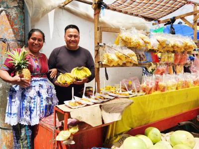 VisionFund client and her husband in front of fruit stand in Guatemala