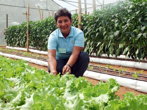 Women showing off her vegetables she grows in her greenhouse in Latin America