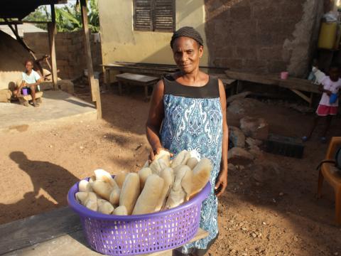 Mercy standing with her basket of bread she sells at the market