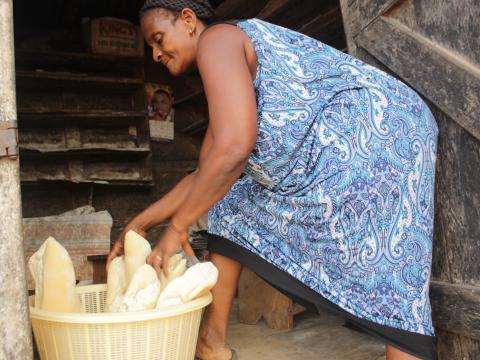 Mercy standing on the stairs of her home in Ghana with bread basket