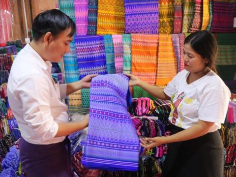 Thin Thin Hlaing showing a client her fabrics she sells in Myanmar