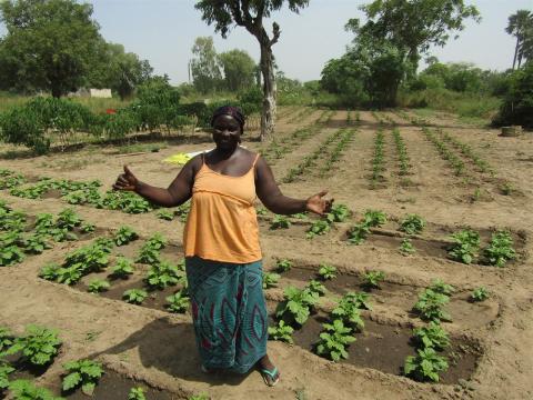 Daba standing with arms open to showcase her thriving gardens. 