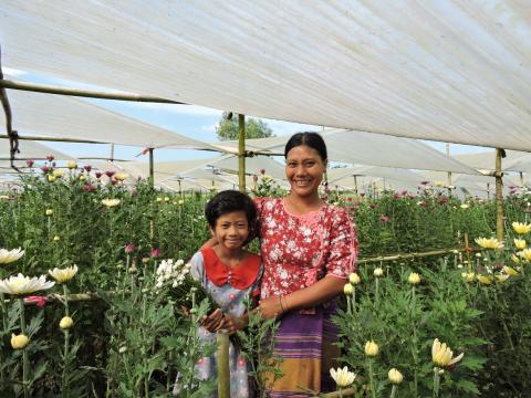 VisionFund client from Myanmar stands in flower garden with her daughter