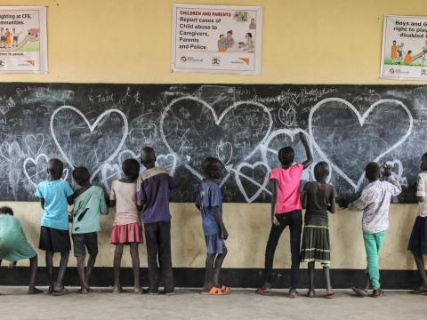 Children draw lovehearts on a chalkboard