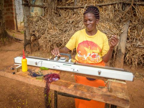 Woman in Kenya working on knitting machine.