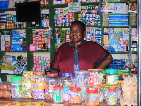 Ugandan woman in front of her grocery stall