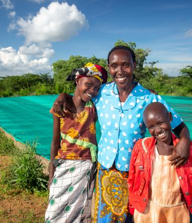 Woman standing beside two children in Kenya