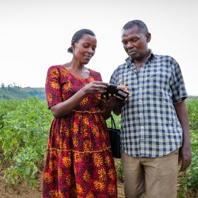 husband and wife looking at mobile phone in farm in Rwanda