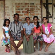 Family sitting in front of their house in Sri Lanka that was built from proceeds from their dairy business. 